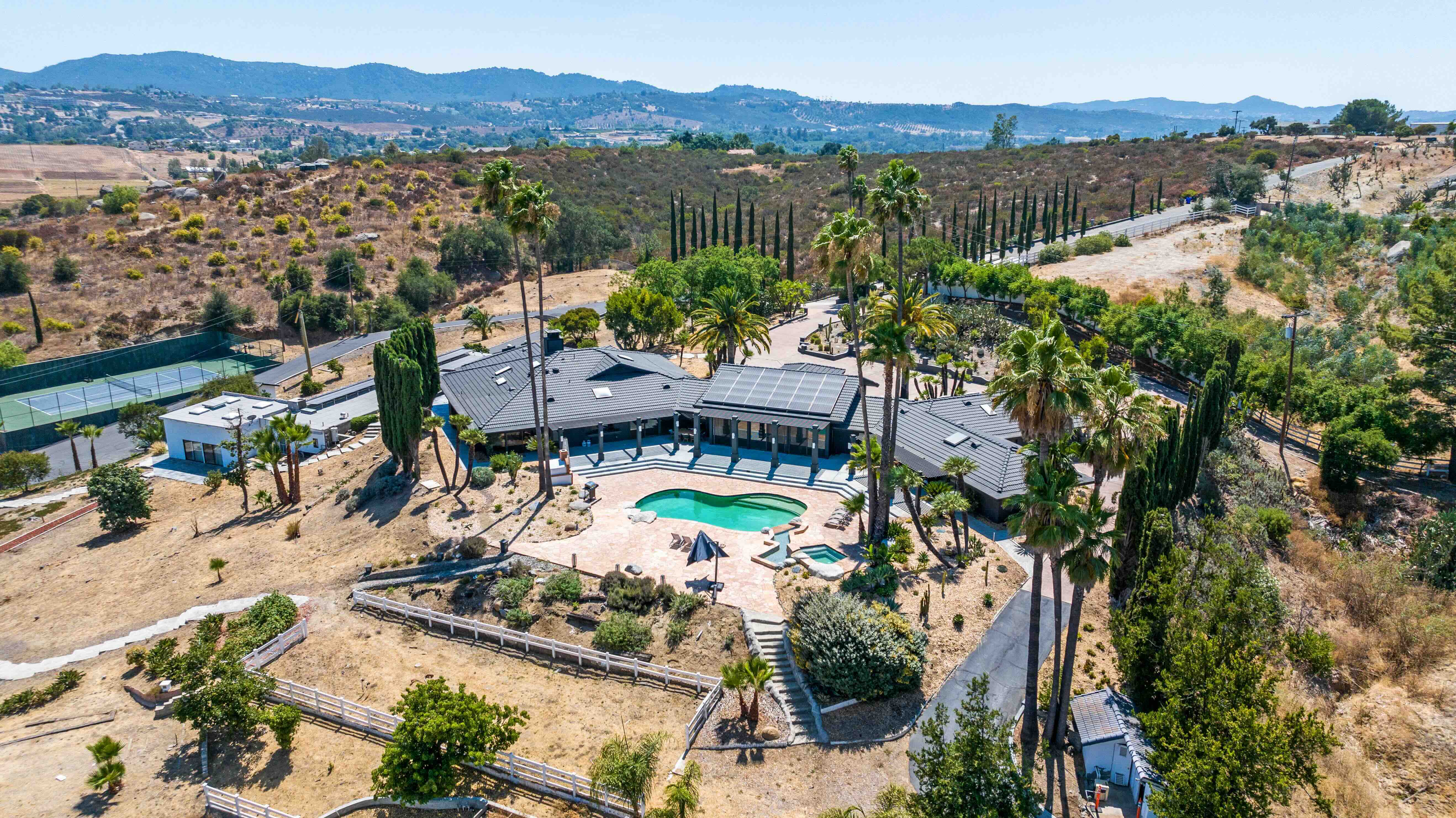 Beautiful aerial view of a private estate wedding venue with swimming pool, palm trees, and mountain backdrop perfect for wedding celebrations